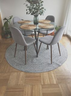 a glass table with four chairs and a rug on the floor in front of it