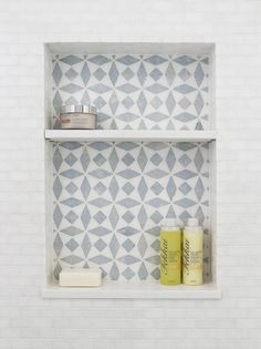 two shelves with different items on them in a white tiled wall behind the toiletries