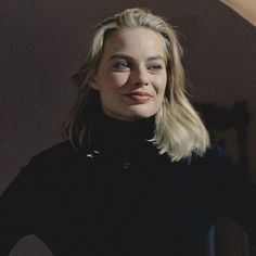 a woman with blonde hair and blue eyes is posing for a photo in a dark room