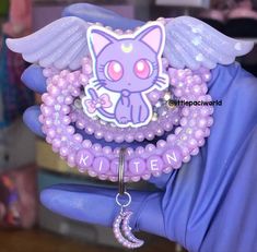 a purple bracelet with an image of a cat on it and angel wings attached to it