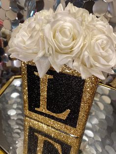 a vase filled with white flowers sitting on top of a table next to confetti