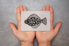 a person holding up a small patch with a fish on it's side,