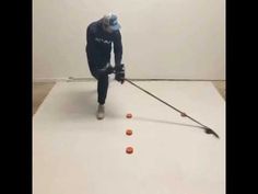 a man in a blue shirt is hitting balls on a white surface with a stick