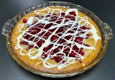 a cake with white icing and strawberries on it sitting in a glass dish