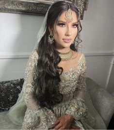 a woman in a bridal gown sitting on a couch with her hair pulled back