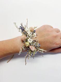 a woman's hand with a bracelet that has flowers on it and branches in the middle