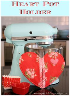 a heart shaped pot holder sitting on top of a kitchen counter next to a mixer