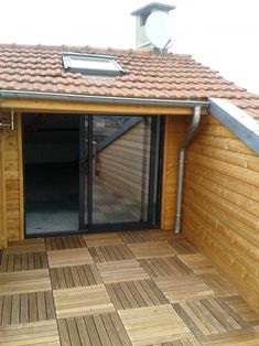 a wooden deck with sliding glass doors and tiled roof