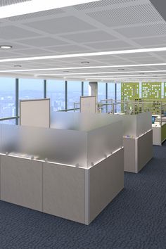 an empty office cubicle with two desks and several screens on the wall, overlooking a city