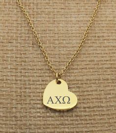 a gold heart necklace with the word tb on it