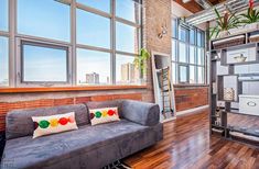 a living room filled with furniture next to a window covered in lots of windows and a ladder