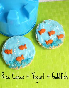 two cookies with blue icing and orange fish on them next to a cookie molder