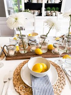 a white table topped with plates and bowls filled with lemons