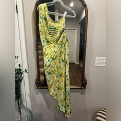 a yellow dress hanging on a hanger in front of a mirror with a plant