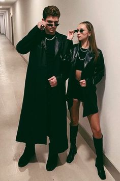 a man and woman standing next to each other in an empty hallway with white walls