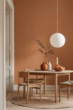 a dining room with an orange painted wall and wooden table surrounded by chairs in the middle