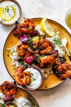 grilled shrimp skewers with lemon - dill sauce on a yellow plate