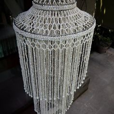 a white chandelier with beads hanging from it's sides in front of a building