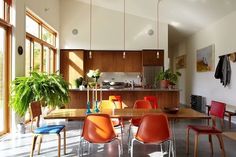 an open kitchen and dining room with lots of chairs around the table in front of large windows