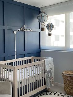 a baby's room with blue walls and white crib in the corner, next to a window