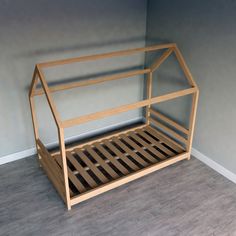 a wooden bed frame sitting on top of a hard wood floor next to a wall