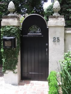 an entrance to a house with a black door and white pillars, surrounded by greenery