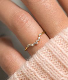 a woman's hand wearing a gold ring with three small diamonds on the band