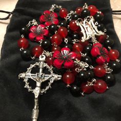 The rosary is made with 22mm Red Hibiscus beads and 10mm Black and Red jade beads. The rosary is a traditional 5 decade catholic rosary.  Center : silver-plated metal *made in Italy* Crucifix: silver plated metal *made in Italy* **All rosary comes with a velvet jewelry bag** Rosary Catholic, Blessed Virgin Mary, Jade Beads, Coin Necklace, Jewelry Bags, Rosary, Antique Gold, Hibiscus, Black And Red