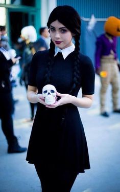 a woman holding a skull in her hand while wearing a black dress and white collared shirt