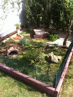 an outdoor area with grass and rocks in the back yard, including a fire pit