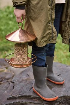 a person holding a bird feeder on top of a rock