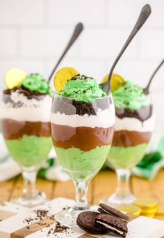 two glasses filled with green and brown desserts on top of a white countertop