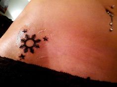 a woman's belly with stars on it and a sun tattoo in the middle