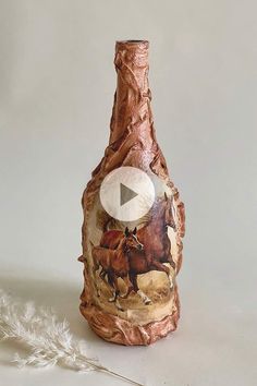 a bottle that has been decorated with horses on it and is next to a feather