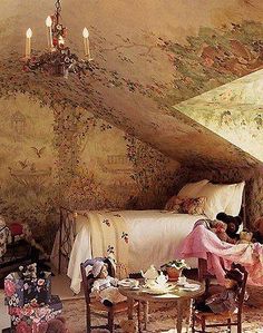 two women sitting at a table in front of a bed with floral wallpaper on it