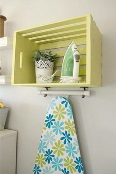 the ironing board is hanging on the wall next to an ironing board and potted plant