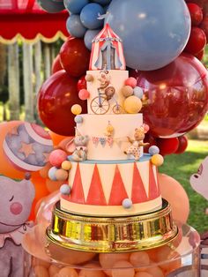 a birthday cake with balloons and decorations on the top is in front of a carousel