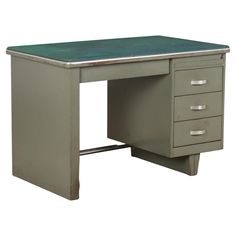 an old metal desk with three drawers and a green top is shown against a white background