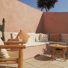 an outdoor seating area with couches, tables and a cactus tree in the background