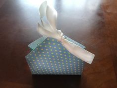 a small blue box with white polka dots and a bow on the top is sitting on a table