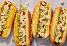 three hot dogs with mustard, onions and lettuce