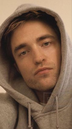 a man in a grey hoodie looking at the camera with an intense look on his face