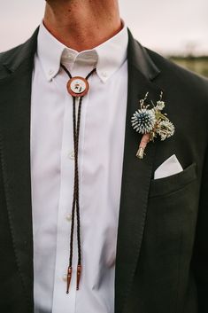 a man wearing a black suit and white shirt with a flower on his lapel