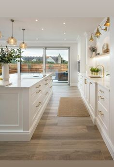 a large kitchen with white cabinets and wood flooring, along with an area rug on the floor