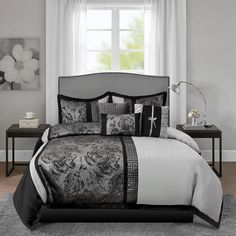 a bed with black and white comforters in front of a window