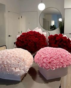 three large roses are sitting on a table in front of a mirror and two round boxes