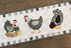 three chickens on a white and black table runner