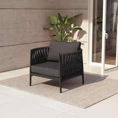 a black chair sitting on top of a rug next to a plant in a pot