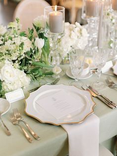 the table is set with white flowers and silverware for an elegant wedding reception or special event