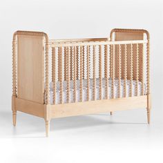 a baby crib made out of wood with white sheets on the bottom and sides